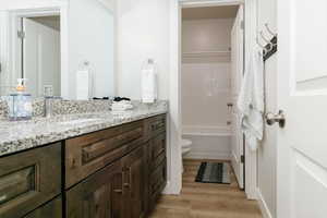 Full bathroom with vanity, shower / bathtub combination with curtain, and light wood-type flooring