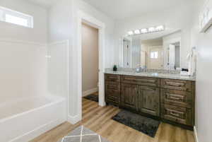 Full bathroom featuring a bath, vanity, and light wood-type flooring