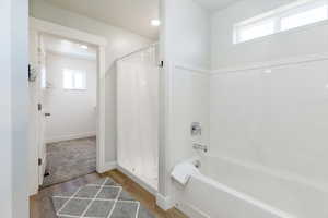 Bathroom with wood finished floors and shower / bath combo with shower curtain
