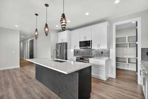 Downstairs ADU. Kitchen with a center island with sink, white cabinetry, decorative light fixtures, decorative backsplash, and recessed lighting