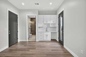 Upstairs studio kitchenette featuring white cabinetry, light wood-style flooring, backsplash, recessed lighting, and open shelves