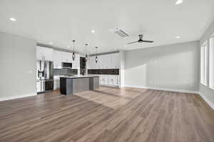 Downstairs ADU. Kitchen with open floor plan, white cabinetry, pendant lighting, stainless steel appliances, and light countertops