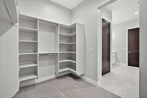 Walk in closet with light colored carpet and light tile patterned floors