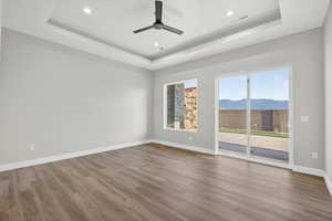 Spare room featuring a raised ceiling, light wood-style flooring, recessed lighting, ceiling fan, and a mountain view
