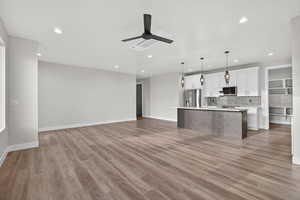 Downstairs ADU. Kitchen featuring open floor plan, white cabinets, hanging light fixtures, tasteful backsplash, and a kitchen island with sink