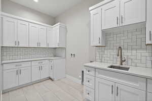 Kitchen with backsplash, white cabinetry, light stone countertops, and light tile patterned floors