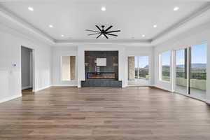 Unfurnished living room with a tray ceiling, a fireplace, recessed lighting, and wood finished floors
