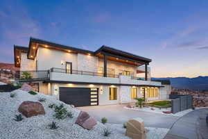 Modern home with stone siding, concrete driveway, an attached garage, and stucco siding