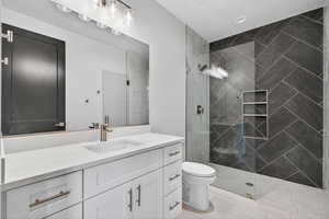Downstairs ADU. Full bath with vanity, a tile shower, and light tile patterned floors