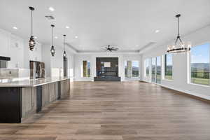 Kitchen featuring pendant lighting, a raised ceiling, white cabinetry, open floor plan, and recessed lighting