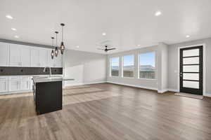 Downstairs ADU. Kitchen with white cabinetry, a center island with sink, hanging light fixtures, a ceiling fan, and backsplash