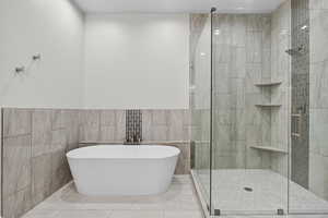 Full bathroom with tile walls, a shower stall, a freestanding bath, and tile patterned flooring