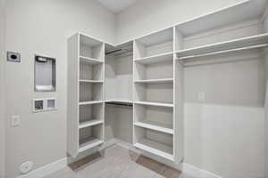Upstairs studio walk-in closet featuring light tile-patterned floors