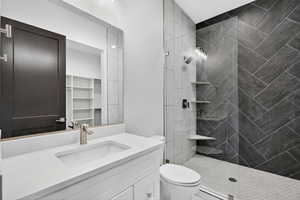 Upstairs studio bathroom featuring a vanity, tiled shower, and a walk-in closet