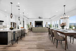 Dining space featuring a tray ceiling, light wood-style flooring, ceiling fan, recessed lighting, and a chandelier