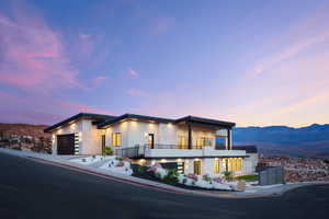 Modern home featuring an attached garage, a mountain view, a balcony, and stucco siding
