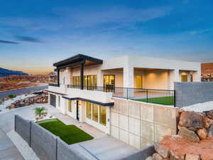 View of front facade featuring stucco siding, a balcony, a garage, and a patio