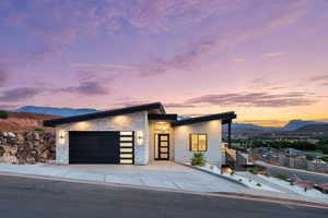 Modern home with stone siding, a mountain view, an attached garage, and concrete driveway