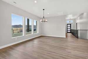Unfurnished dining area featuring a chandelier, light wood-style flooring, and recessed lighting