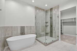 Bathroom with a stall shower, a freestanding tub, tile walls, a spacious closet, and recessed lighting