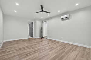Unfurnished bedroom featuring recessed lighting, light wood-type flooring, a ceiling fan, and a wall mounted AC
