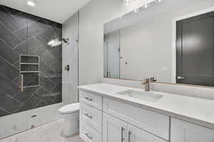 Downstairs ADU. Bathroom featuring vanity, tiled shower, and light tile patterned flooring