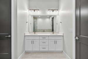Full bathroom featuring double vanity, a stall shower, and light tile patterned flooring