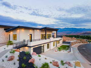 View of front facade with stucco siding, a garage, a tiled roof, a balcony, and concrete driveway