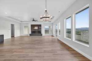 Unfurnished living room with a raised ceiling, a chandelier, light wood-style flooring, recessed lighting, and a mountain view