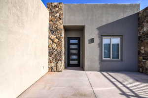 Doorway to property featuring stone siding and stucco siding