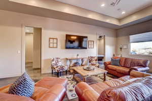 Living room with recessed lighting, concrete flooring, and a tray ceiling