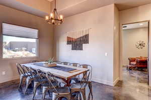 Dining area with finished concrete flooring and a chandelier