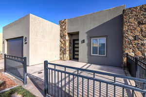 View of front of property featuring stucco siding, an attached garage, a patio, and concrete driveway