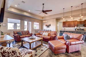 Living area featuring a tray ceiling, ceiling fan, recessed lighting, french doors, and a chandelier