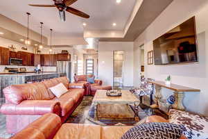 Living room featuring a ceiling fan, a raised ceiling, and recessed lighting
