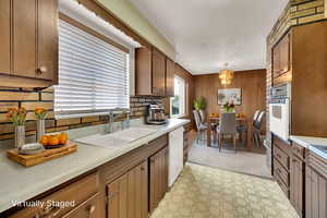 Kitchen with light countertops, backsplash, decorative light fixtures, a chandelier, and white appliances