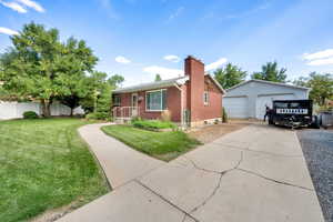View of front of house featuring a detached garage, an outbuilding, a chimney, and brick siding