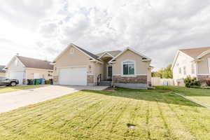View of front facade featuring stucco siding, stone siding, driveway, and an attached garage