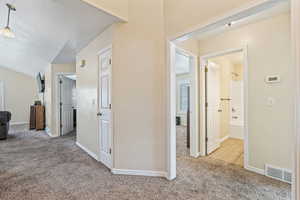 Corridor with light colored carpet and a textured ceiling