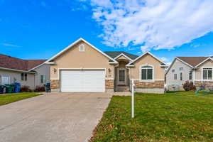 Craftsman-style home featuring stucco siding, stone siding, a front lawn, concrete driveway, and a garage