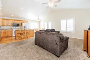 Living area featuring light carpet, high vaulted ceiling, recessed lighting, and a ceiling fan