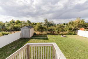 Fenced backyard featuring a storage unit, an outdoor fire pit, and a balcony