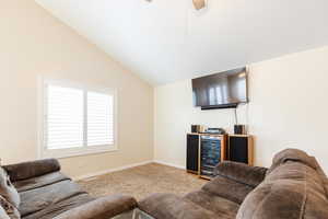Living area with light colored carpet, vaulted ceiling, ceiling fan, and beverage cooler