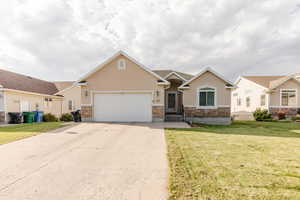 Craftsman inspired home featuring stone siding, stucco siding, a garage, concrete driveway, and a front lawn