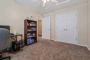 Carpeted home office with ceiling fan and baseboards