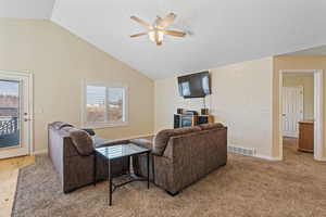Living area with lofted ceiling, a ceiling fan, and light colored carpet