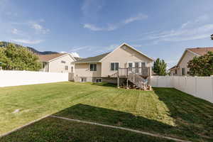 Rear view of house with a fenced backyard, a wooden deck, and stairway