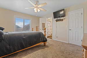 Bedroom featuring ensuite bathroom, carpet floors, and a ceiling fan