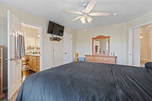 Carpeted bedroom featuring ceiling fan and connected bathroom