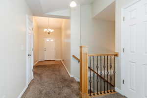 Corridor with carpet flooring, an upstairs landing, and a chandelier